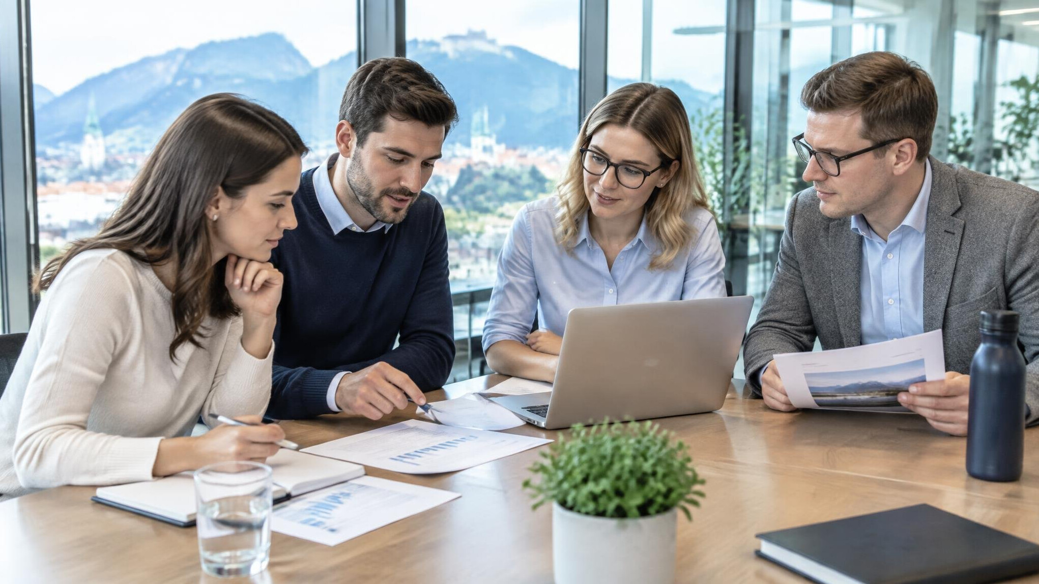 Small diverse team discussing documents around a table in a bright meeting room